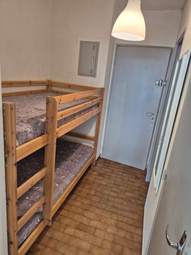 Cette chambre comprend 2 lits superposés et une porte. dans l'établissement La Désirade J, Studio rénové avec parking, centre port, au Cap d'Agde