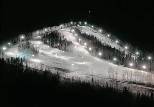 a snow covered road with street lights at night at Nice ski in ski out cabin in Bollnäs