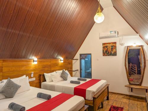 a bedroom with two beds and a wooden ceiling at Sigiri Choona Lodge 'unique sunrise viewpoint' in Sigiriya