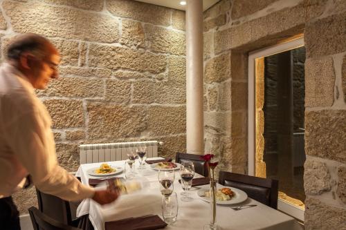 a man standing in front of a table with plates of food at Casas Novas Countryside Hotel Spa & Events in Chaves