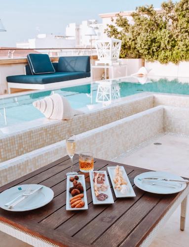 a table with plates of food and a glass of wine at Palazzo del Corso – Boutique Hotel in Gallipoli