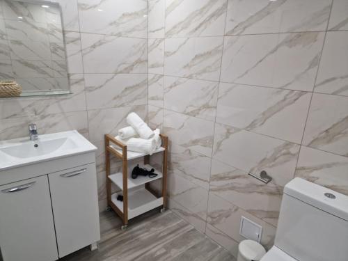 a bathroom with a white sink and a marble wall at Apartamente Topaz Sea View Olimp in Olimp
