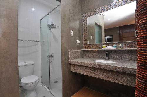 a bathroom with a toilet and a sink and a mirror at 717 Cesar Place Hotel in Tagbilaran City