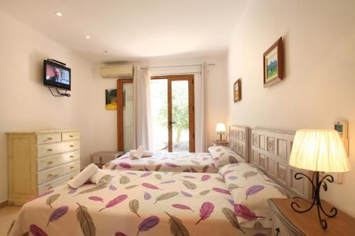 a bedroom with two beds and a dresser and a television at Ca Na Barbara in Santanyi