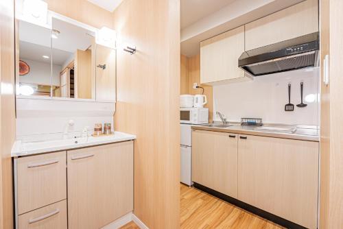 a small kitchen with white cabinets and a sink at skytree Family Hotel in Tokyo