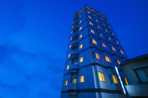 a blue building with illuminated windows against a blue sky at Hotel Meijiya in Hamamatsu