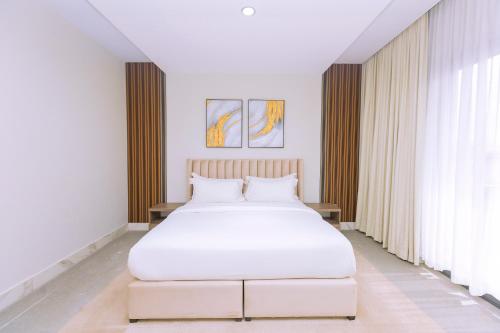 a bedroom with a white bed and a large window at Paradise Court by LLA in Accra
