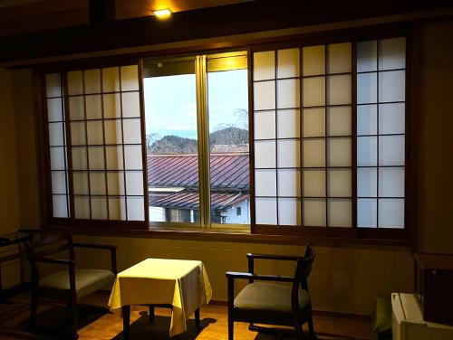 a room with a table and chairs and windows at Chikurinin Gunpoen in Yoshino