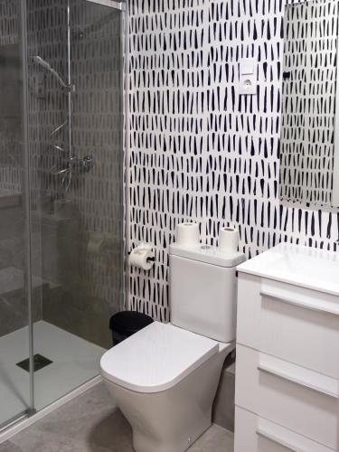 a white bathroom with a toilet and a shower at Pension Roomtegi in Barakaldo