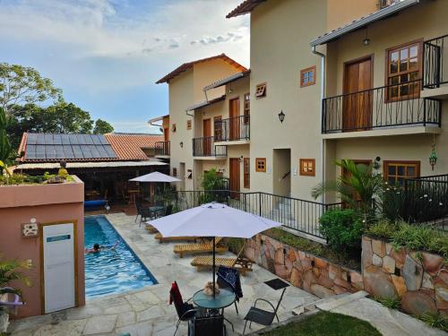 an outdoor patio with an umbrella and a swimming pool at Pousada Mãe Natureza in Pirenópolis
