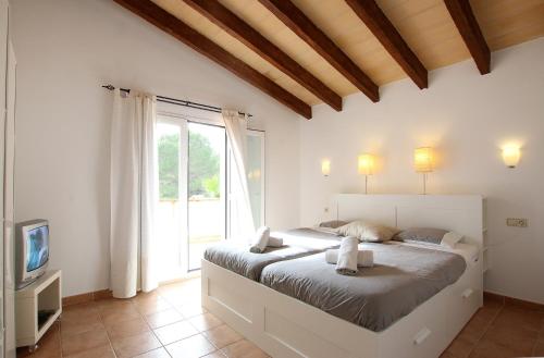 a bedroom with a large bed and a tv at Son Cami in S'Horta