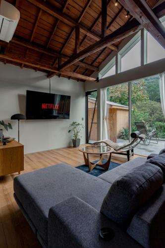 Una sala de estar con un sofá y un televisor. en サウナ付き一棟貸し宿 築ける宿 - sudaku, en Iwada