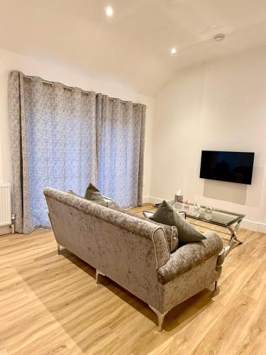 a living room with a couch and a flat screen tv at Bespoke 1 Bedroom Barn by Stansted Airport & Holiday Parking in London Stansted Airport