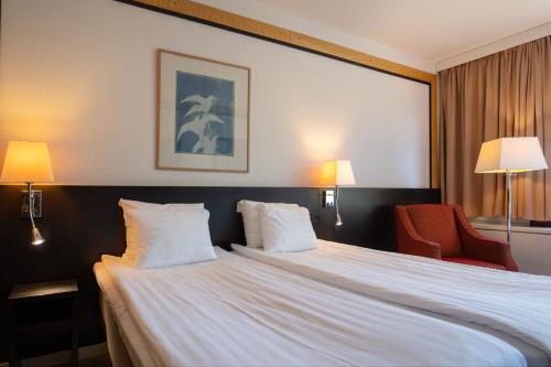 a hotel room with a large bed and a red chair at Hotel Korpilampi in Espoo