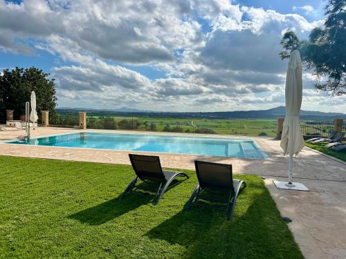 two chairs and an umbrella next to a swimming pool at Mater Ariany in Ariany