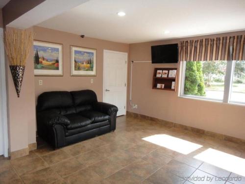 a living room with a black leather couch and a window at Motel 6-Richmond, VA - Midlothian Turnpike in Richmond