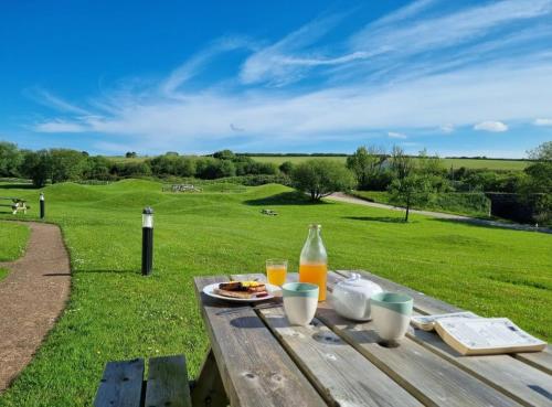 ein Picknicktisch mit einem Teller Essen und Orangensaft in der Unterkunft Sandpiper Cottage: cosy home near the beach in Woolacombe