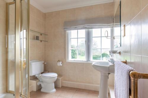 a bathroom with a toilet and a sink and a window at East House in High Legh