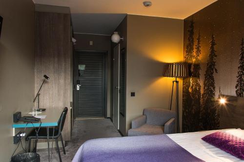 a bedroom with a bed and a desk and a chair at Hotel Korpilampi in Espoo