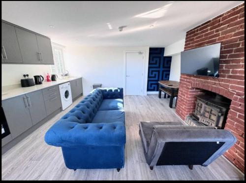 a living room with a blue couch and a brick fireplace at Canterbury Castle Lodge - 8 Bedroom Retreat in Canterbury