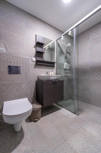 a bathroom with a toilet and a sink and a shower at GERANIUM Holliday Villas in Obrochishte