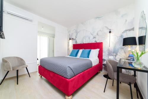 庞特卡格纳诺Shamika Luxury Rooms的一间卧室配有红色的床和一张书桌