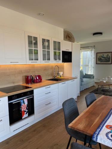 a kitchen with white cabinets and a table and a dining room at Apartmán na úpatí Šumavy in Stachy