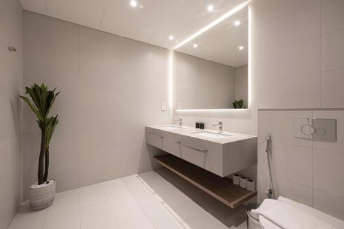 a white bathroom with a sink and a mirror at La Vie in JBR! Private Beach! Excellent Apartments! in Dubai