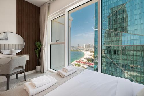 a bedroom with a bed and a desk and a large window at La Vie in JBR! Private Beach! Excellent Apartments! in Dubai