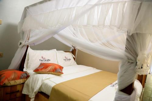 a bedroom with a canopy bed with white sheets and pillows at The Giraffe Cottages in Nairobi