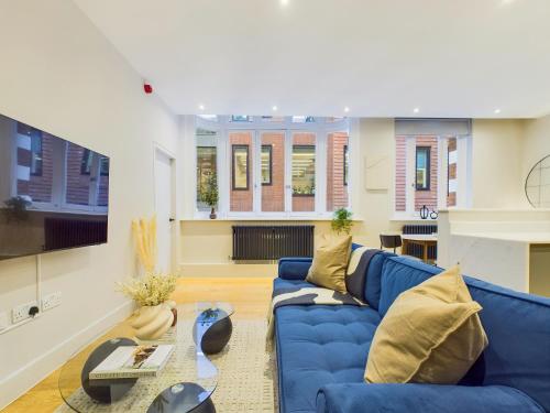 a living room with a blue couch and a table at Be London - The Piccadilly Circus Residences in London