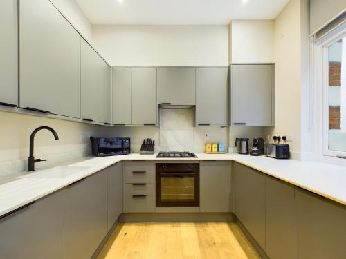 a kitchen with white cabinets and a sink at Be London - The Piccadilly Circus Residences in London