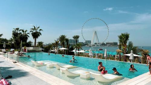 a group of people in a swimming pool at a resort at La Vie in JBR! Private Beach! Excellent Apartments! in Dubai