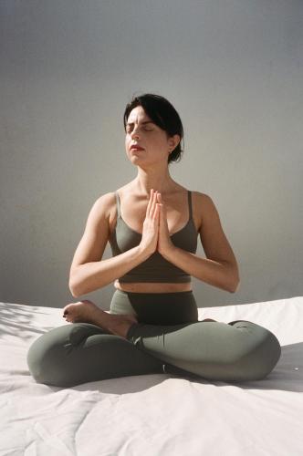 a woman sitting on a bed doing a yoga pose at Palazzo del Corso – Boutique Hotel in Gallipoli