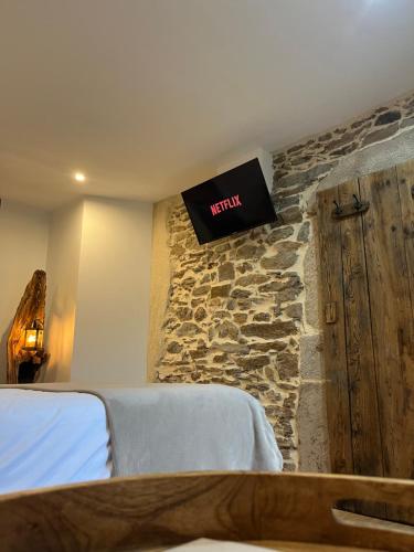 sypialnia z łóżkiem i telewizorem na kamiennej ścianie w obiekcie La Voûte du Pilat & options SPA, massage w mieście Saint-Chamond