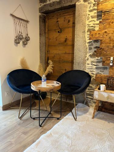 dwa krzesła i stół w pokoju w obiekcie La Voûte du Pilat & options SPA, massage w mieście Saint-Chamond