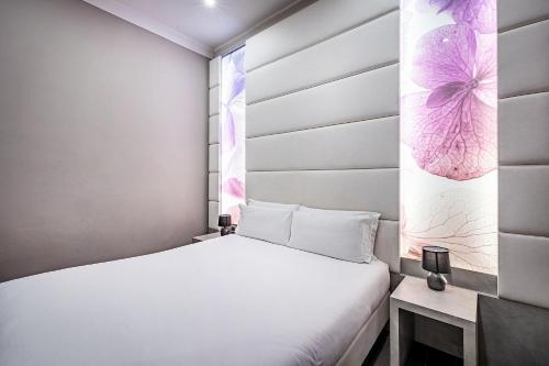 a small bedroom with a white bed and a pink flower painting at B&B Residenza le Fonticine in Florence