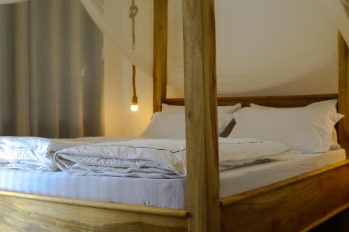 a wooden bed with white sheets and pillows at Hakuna in Arusha