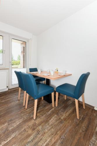 a dining room with a table and blue chairs at Zur Möwe 5 in Esens