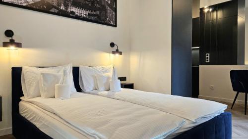 a bedroom with a large bed with white sheets and pillows at ROOSEVELTA RESIDENCE Apartments - przy OFF Piotrkowska in Łódź