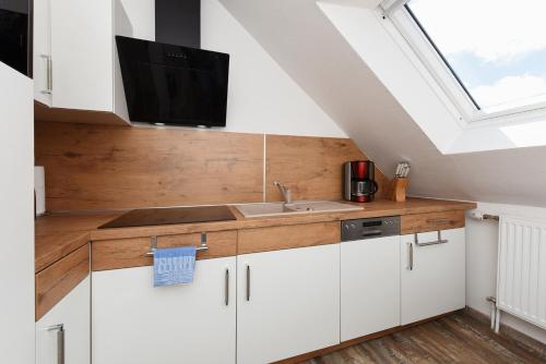 a kitchen with white cabinets and a sink and a window at Zur Möwe 4 in Esens