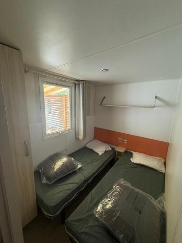 deux lits dans une petite pièce avec une fenêtre dans l'établissement Mobil-home, à Agde