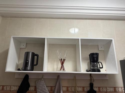a white cabinet with utensils and appliances on it at Appartement meublé type F2 in Douala