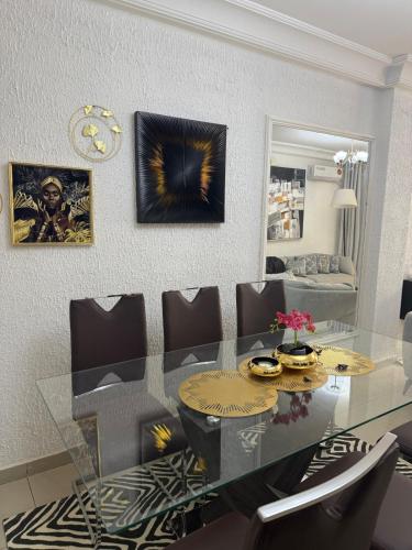 a dining room with a glass table and chairs at Appartement meublé type F2 in Douala