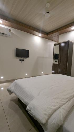 a bed in a room with a tv on the wall at The grange sunrise view in Panchgani