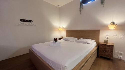 a bedroom with a large white bed with a vase on it at SUITE LA SERENITA - JACUZZI - CLIM - WIFI - TopProsConciergerie in Saint-Georges-dʼOrques