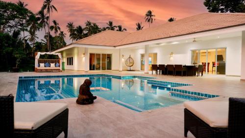 a person sitting in front of a swimming pool at Villa sun in Amphoe Koh Samui