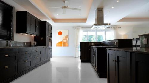 a kitchen with black cabinets and a ceiling fan at Villa sun in Amphoe Koh Samui