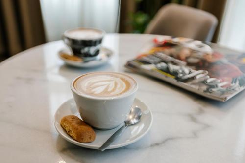 a cup of coffee and a cookie on a table at Hotel Bloemendaal by BHC in Bloemendaal