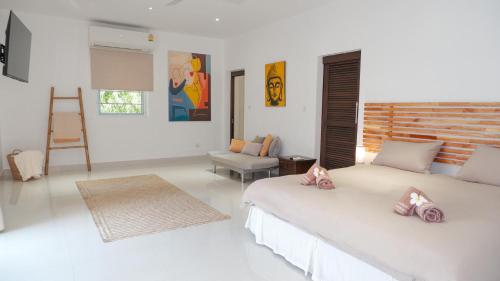 a white bedroom with two beds and a chair at Villa sun in Amphoe Koh Samui